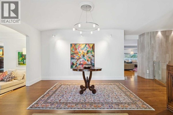 Foyer with hardwood floors, modern chandelier, and a colorful abstract painting. - 88 Massey Place Sw, Calgary