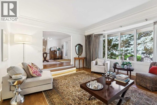 Living room with bay windows, a sectional sofa, and an archway to another room. - 88 Massey Place Sw, Calgary