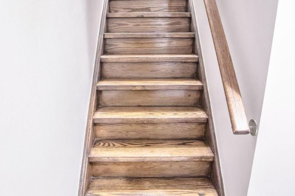 Wooden staircase with light brown treads and a wood handrail against a white wall. - 88 Robert Parkinson Drive, Brampton