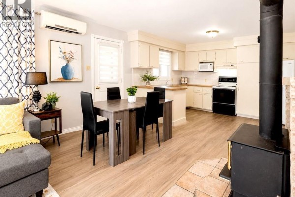 Open-concept living and kitchen area featuring a sofa, dining table, and wood-burning stove. - 88 Rue Donat, Pointe Des Robichaud