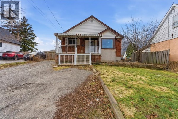 Side view of the house featuring the porch and surrounding yard. - 880 Lawrence Road, Hamilton