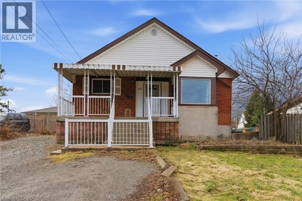 Front view of the house with porch, gravel driveway, and landscaping details. - 880 Lawrence Road, Hamilton