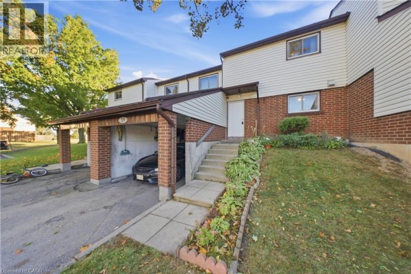 Townhouse exterior showing carport, brick accents, white door, and steps to front entrance. - 880 Limeridge Road E Unit# 59, Hamilton