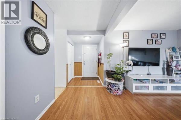 Living room with wood floors, light grey walls, white trim, and doorway to hallway. - 880 Limeridge Road E Unit# 59, Hamilton