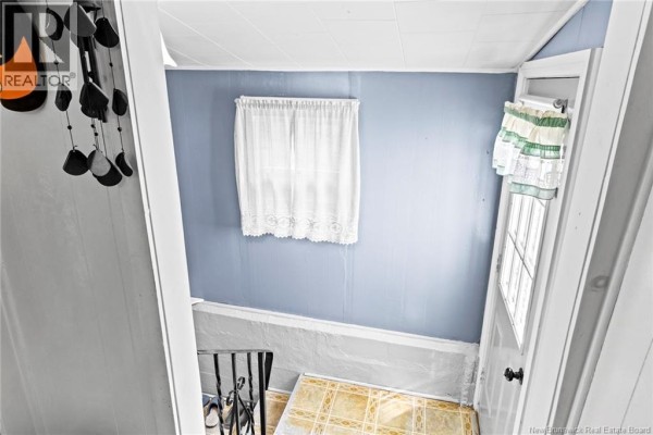 Interior view of a narrow hallway with a small window, blue walls, and stairs leading down. - 880 Pleasant Drive, Minto
