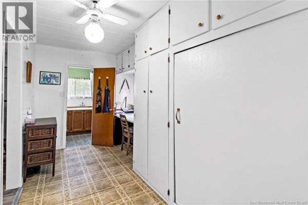 Interior hallway with tiled floor, white cabinets, a desk, and a doorway to a kitchen area. - 880 Pleasant Drive, Minto