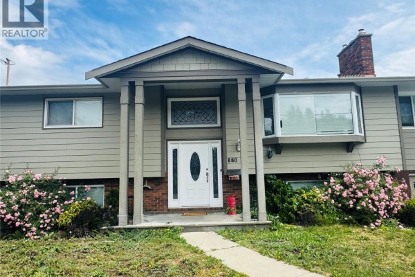 Front view of house with white door, brick accents, and green siding. - 880 Tamarack Drive, Kelowna