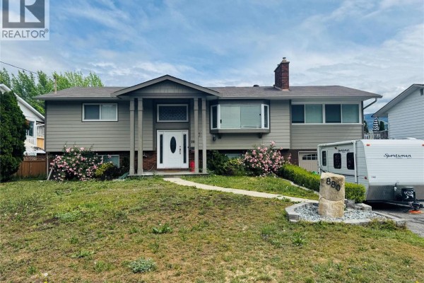 Exterior view of house with beige siding, bay window, and RV parked. - 880 Tamarack Drive, Kelowna