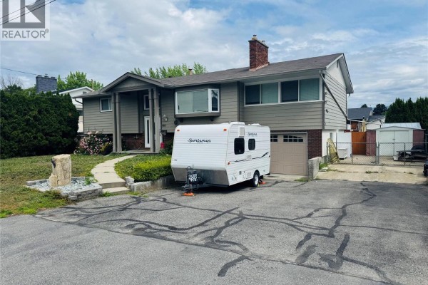Driveway with an RV, garage, and a stone marker with number 880. - 880 Tamarack Drive, Kelowna