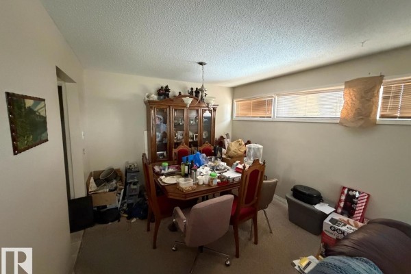 Dining room featuring a wooden table with upholstered chairs, a china cabinet, and carpeted flooring. - 8816 137 Av Nw, Edmonton