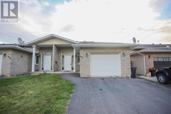 View of a bungalow's facade with dual front doors, garage, and tan brick exterior. - 882 Pine St, Sault Ste  Marie