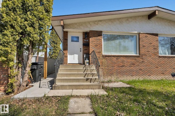 Close-up of the front door with a white door, glass pane, and concrete steps. - 8823-8825 95 St Nw, Edmonton
