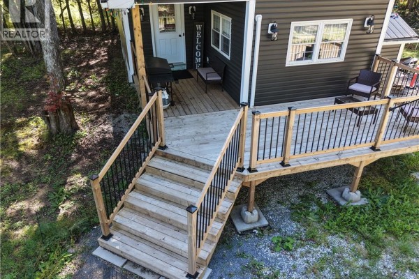 Wooden deck and stairs leading to the front porch of the dark brown bungalow. - 883 Route 855, Midland