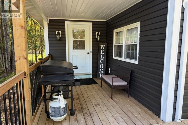 Front porch with a grill, bench, and welcome sign next to the front door. - 883 Route 855, Midland
