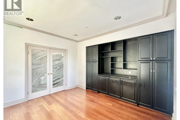 Den with dark wood built-in cabinetry and French doors. - 883 W 52 Avenue, Vancouver