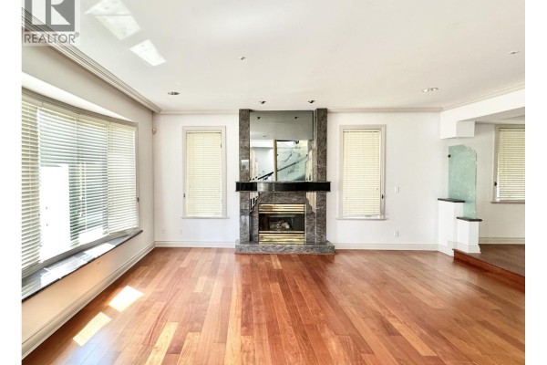 Living room with a marble fireplace, large windows, and hardwood floors. - 883 W 52 Avenue, Vancouver