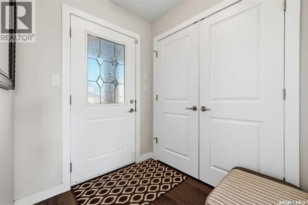 Interior entryway with a white door, glass panels, and a dark patterned rug. - 8837 Kestral Drive, Regina