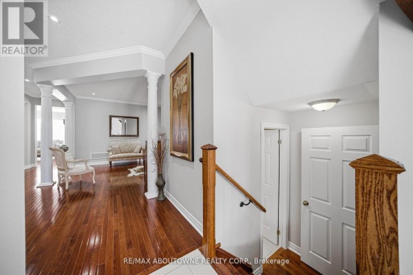 Hallway with hardwood floors, columns, leading to a living area with sofas. - 884 Stoutt Crescent, Milton