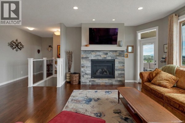 Kitchen with dark wood cabinets, granite countertops, a central island, and stainless steel appliances. - 885 Timberline Dr, Campbell River
