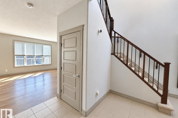 Kitchen with dark wood cabinets, stainless steel appliances, and an open view to the living room. - 885 Windermere Wd Nw, Edmonton