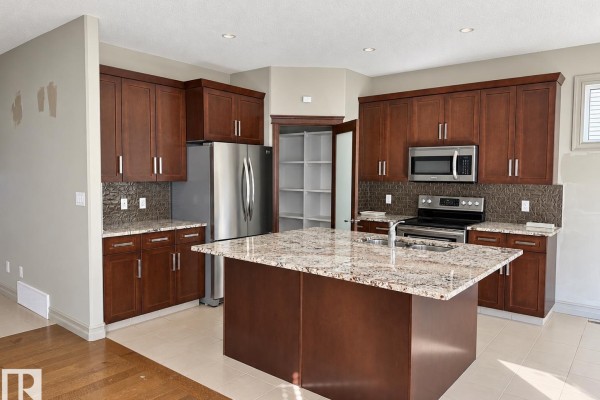 View of the kitchen, stainless steel refrigerator, and a door leading to an outdoor deck. - 885 Windermere Wd Nw, Edmonton