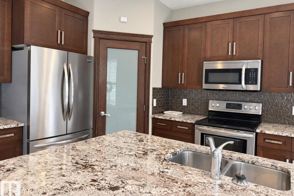 Walk-in closet with white shelving and a doorway showing a laundry room with a washing machine. - 885 Windermere Wd Nw, Edmonton