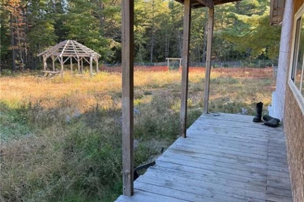 Wooden porch with tall grass and a gazebo in the background, overlooking the yard. - 886 Cains River Road, Cains River