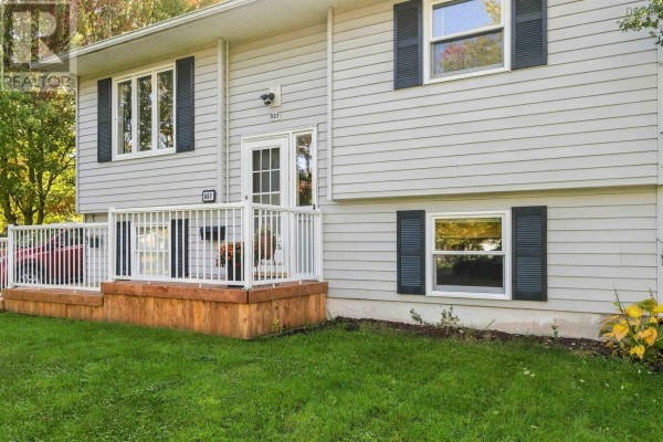 Detailed view of the front entrance of the light grey house, showing windows, railings, and siding. - 887 Richard Street, Kentville