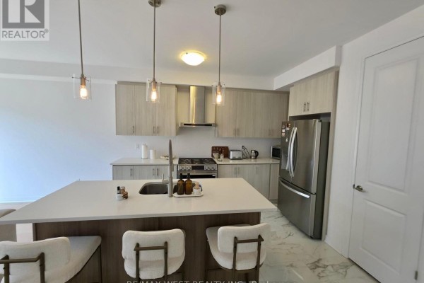 Kitchen with light wood cabinetry, stainless steel appliances, and a large island with pendant lights. - 889 Douro Street, Stratford