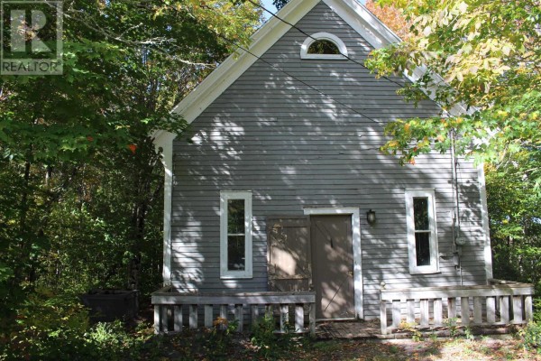 Front view of a grey, weathered wood house with a small porch and arched window. - 889 Highway 246, Wentworth