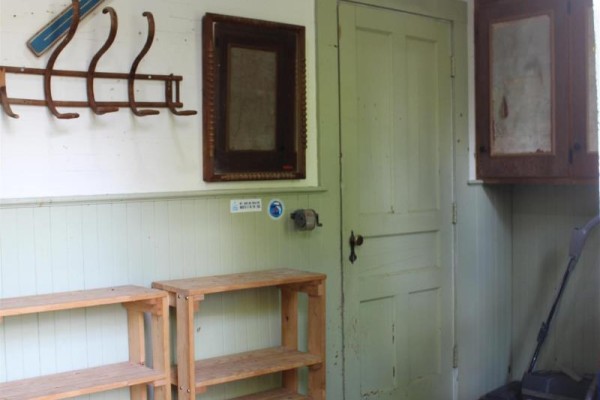 Interior view of a mudroom with wooden shelves, hooks, a mirror, and a light green door. - 889 Highway 246, Wentworth