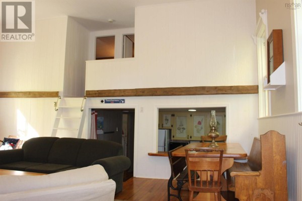 Living area with a sofa, dining table, loft access via ladder, and kitchen view. - 889 Highway 246, Wentworth