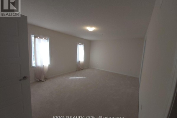 Empty bedroom with neutral carpet, white walls, and two windows with sheer curtains. - 8895 Chickory Trail, Niagara Falls