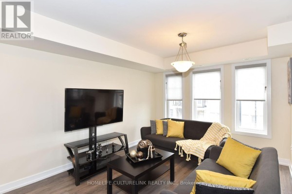 Living space with two dark grey sofas, a coffee table, and television on a stand. - 89 - 100 Parrotta Drive, Toronto