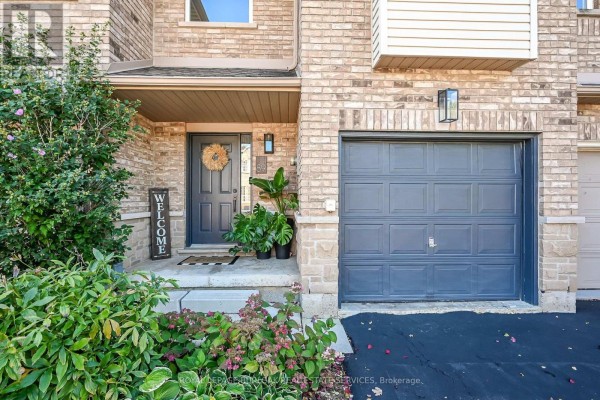 Close-up of the townhouse front door with a welcome sign and plants. - 89 - 4055 Forest Run Avenue, Burlington