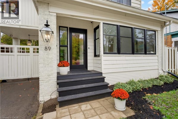 Close-up of the front porch with dark gray steps, white brick accents, a black door, and large windows. - 89 Allen Street W, Waterloo