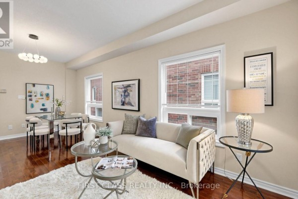 Living room and dining area with beige walls, hardwood floors, sofa, dining table, and chandelier. - 89 Castan Avenue, Markham