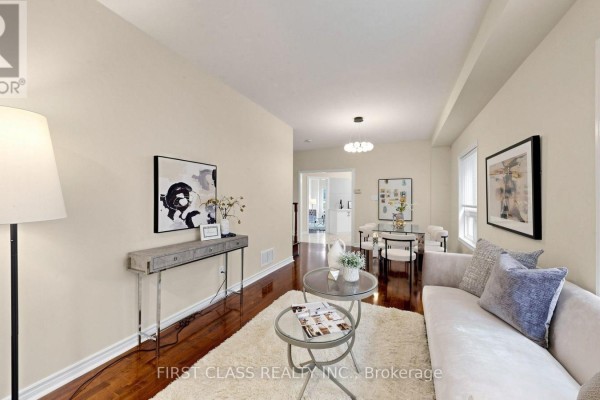 Living area with sofa, coffee tables, and console table, overlooking dining area with chandelier. - 89 Castan Avenue, Markham
