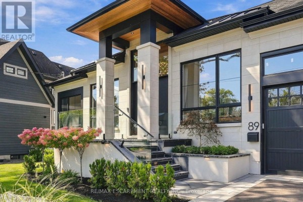 Close-up of the modern home entrance with stone pillars, glass railings, and landscaping. - 89 Cumberland Drive, Mississauga