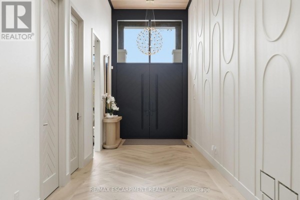 Elegant home entryway with black double doors, a statement chandelier, and decorative wall panels. - 89 Cumberland Drive, Mississauga