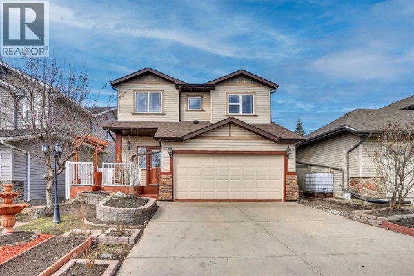 Front exterior of a two-story house with beige siding and a beige garage door during the day. - 89 Everoak Drive Sw, Calgary