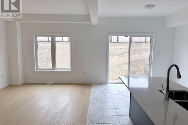 Open concept living area with hardwood and tile flooring, large windows, and patio doors to the backyard. - 89 Flan Boulevard, Barrie