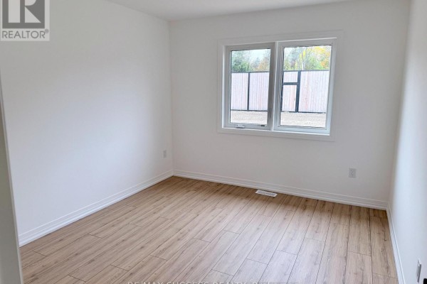 Empty bedroom with light wood laminate flooring, white walls, and a large window. - 89 Flan Boulevard, Barrie