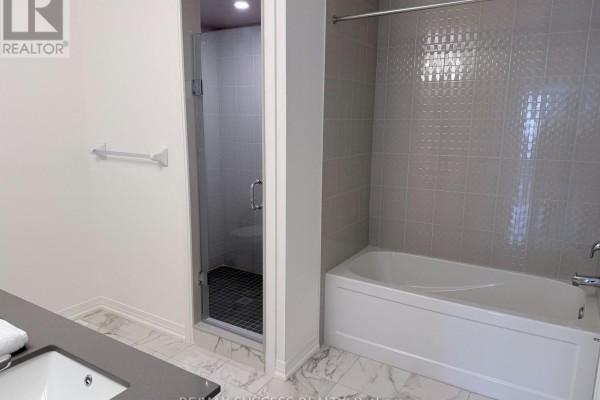 Bathroom with a freestanding bathtub, a glass-enclosed shower stall, and light grey tiled walls. - 89 Flan Boulevard, Barrie