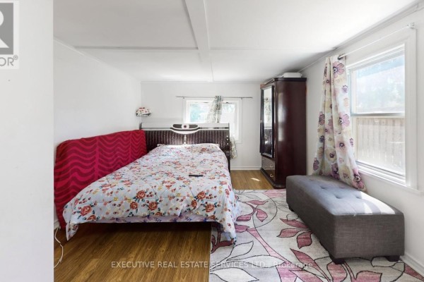 Bedroom with floral comforter, wood wardrobe, and upholstered bench - 89 John Street Brampton