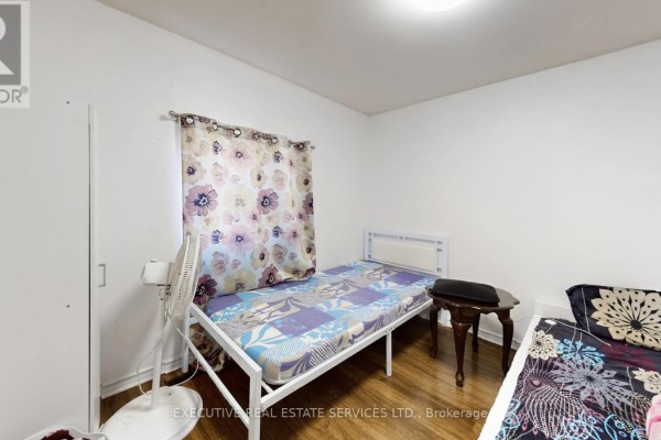 Bedroom with white metal bed and floral curtains - 89 John Street Brampton