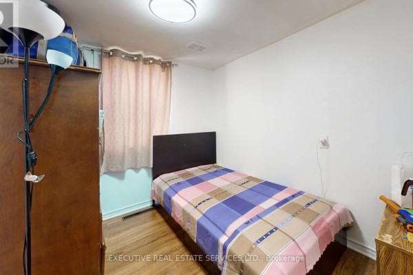 Bedroom with twin bed, wooden wardrobe, and floor lamp - 89 John Street Brampton