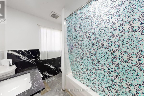 Bathroom with sink, toilet, tub, and black marble accents - 89 John Street Brampton