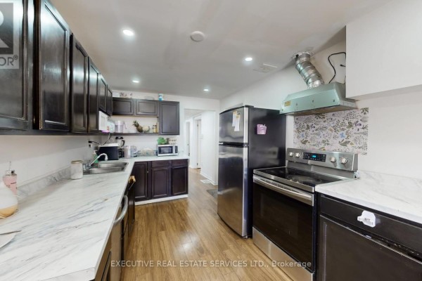 Kitchen with dark cabinets, stainless steel appliances, and marble countertops - 89 John Street Brampton