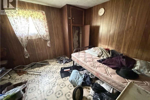 Bedroom with a mattress on the floor, wood-paneled walls, and floral curtains. - 89 Lebel Road, Anfield